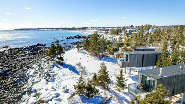 Aerial view of rectangle-shaped cabins along side the ocean in the snow