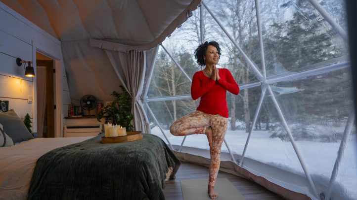 Women wearing read doing a yoga pose in a dome hotel in the winter